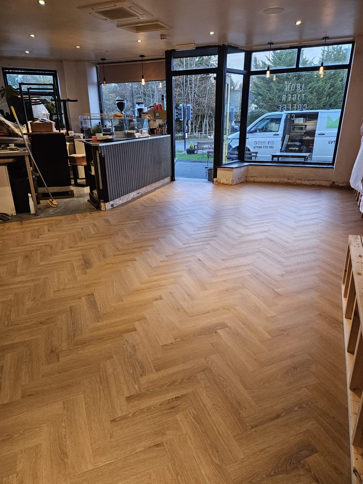 Finished herringbone LVT floor at the front of Iron Tiger Coffee Co with the counter and shop window